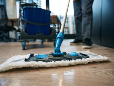 Work of cleaning company specialists in the coworking area, workers use a mop and buckets on a special cart